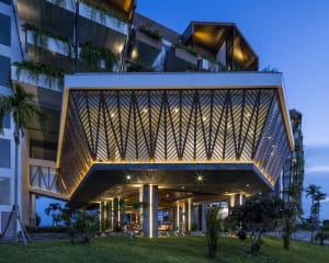 A modern residential building entrance featuring an aluminum-framed canopy with a geometric design.