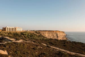 A coastal landscape featuring cliffs, ocean, and rugged terrain.