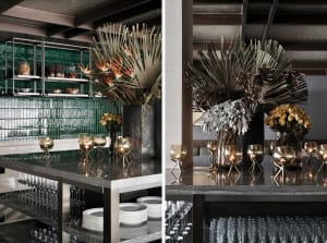 Modern bar interior with glass shelves, metal accents, and decorative metal plants.