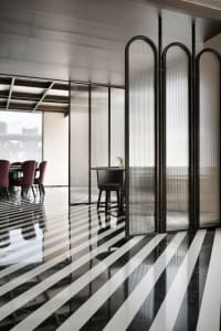 A modern restaurant interior with black and white striped flooring and glass walls.
