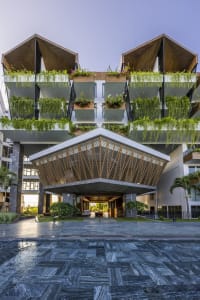 A modern hotel facade with wooden balconies covered in green plants.