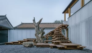 A minimalist outdoor space featuring wood, stone, and metal elements.