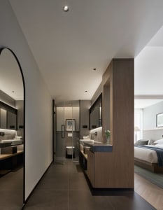 Modern minimalist bathroom with concrete walls and flooring, featuring sleek black fixtures and a large mirror.
