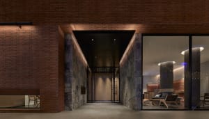 Modern hotel lobby with brick walls and concrete pillars, illuminated by warm lighting.