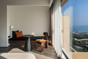 A modern hotel room featuring a minimalist interior design with a large window offering a scenic view of the city and the oce
