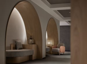A modern minimalist hotel treatment room with wooden accents and cozy seating arrangements.