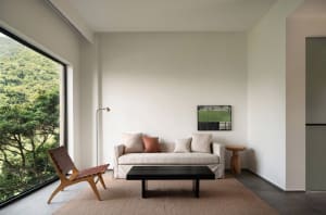 Modern minimalist living room with a white sofa, black coffee table, and a view of the mountains.