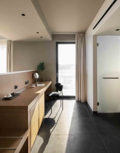 A modern residential interior featuring wooden furniture, concrete flooring, and glass doors.
