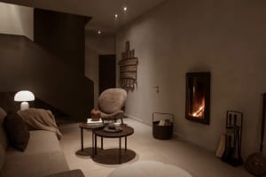 A cozy, modern residential space featuring concrete walls and a plush, comfortable seating area with a fireplace.