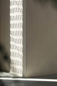 A minimalist architectural design with a shadow pattern on a textured wall.