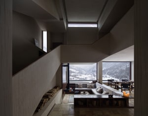 Modern living room with concrete materials and ample natural light.