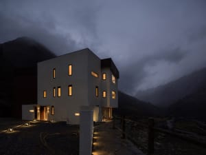 Modern residential exterior with glass windows against a dark, cloudy sky.