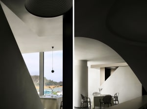 A modern restaurant interior with minimalist design and white concrete walls.