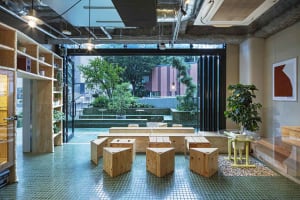 Industrial-style cafe interior featuring wooden furniture and plants.