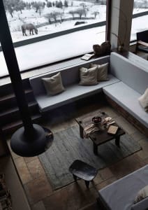A modern living room with a wood and concrete floor, a sectional sofa, and a hanging fireplace.