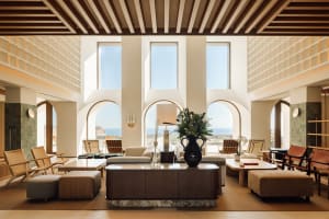 A modern hotel lobby featuring natural light through large windows and contemporary furniture.