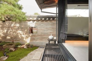 A view of a modern minimalist residential exterior with stone walls and wooden elements.