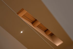 A modern ceiling design featuring exposed wooden roof trusses and recessed lighting.