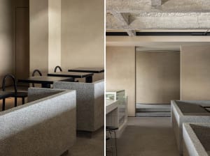 Tables and seating areas of a minimalist restaurant interior, featuring concrete materials and a neutral color palette.