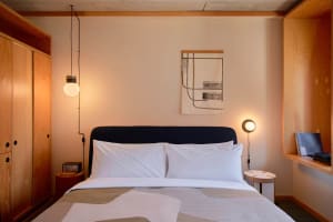 A minimalist bedroom featuring wooden walls, fabric bedding, and metal accents.