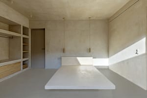 Modern minimalist bedroom with concrete furniture and walls