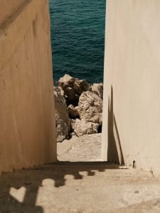 A concrete pathway leading to water, framed by tall walls.