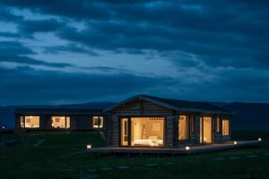 A rustic home with wooden exterior and illuminated windows at night.