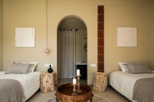 A minimalist bedroom with earth-toned bedding, wooden furniture, and decorative elements.