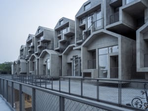 Modern concrete townhouses with exposed concrete walls and balconies.