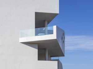 Modern concrete facade with glass balcony.