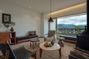 Modern living room with concrete table, leather chairs, and large window overlooking mountains.
