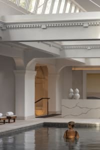 A woman relaxing in a modern indoor relaxation pool made of concrete.