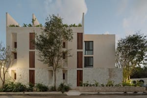Modern building with concrete and stone walls, glass windows, and greenery.
