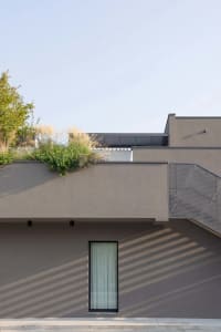 Modern building with concrete facade and rooftop garden with greenery and plants.