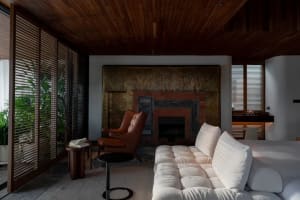 Modern living room with white couch, wooden ceiling, and fireplace.