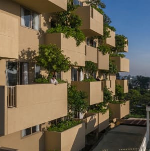 Modern apartment building with concrete balconies adorned with lush greenery and plants.