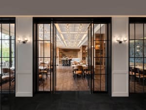 Industrial-style cafe interior with wooden floors, glass walls, and metal furniture.