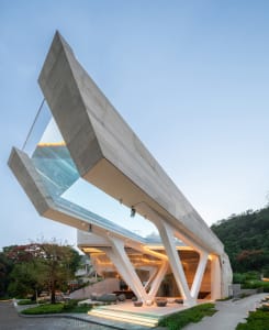 A modern building with a concrete and glass exterior, featuring an angular, open design.