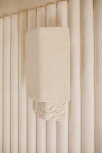 A minimalist architectural concrete detail hanging on a vertical column structure.