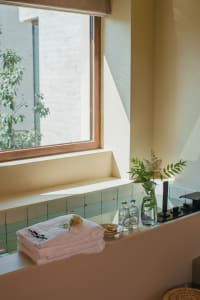 A minimalist bathroom featuring stone tiles and a window with greenery outside.