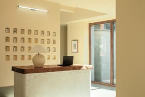 A minimalist office with a concrete front desk featuring a laptop and table lamp.