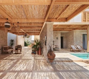 A modern residential patio featuring a concrete floor and a swimming pool surrounded by a wooden pergola structure.