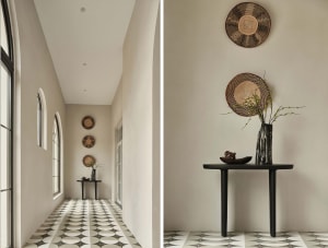 A modern interior corridor featuring concrete walls and patterned tiles with decorative woven baskets hanging on the walls.