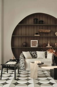 Modern living room with a round wooden shelf, a white sofa with black and white floral upholstery, and marble and concrete fu