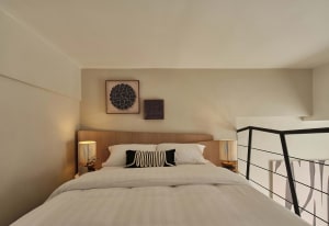 A modern bedroom features minimalist lighting and a comfortable bed with white bedding and black and white accent pillows.