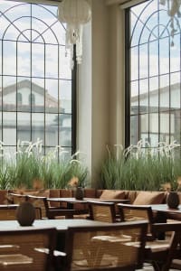 Modern, industrial restaurant interior with large glass windows, minimalist decor, and natural light.
