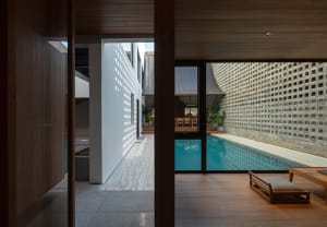 A modern house with a wooden interior featuring a pool and glass walls.