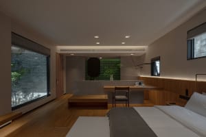 A minimalist bedroom with a concrete wall and wood floor, featuring a large bed and a small table with a chair.