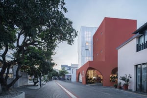 Urban street scene featuring a modern architectural building with red, white, and glass elements.