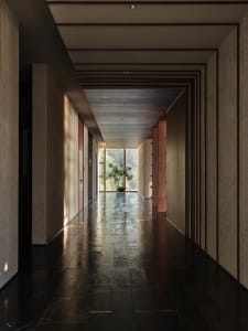 Long, illuminated corridor featuring granite walls and floor, with a potted plant at the far end.